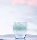 above the clouds, teal and silver, hand-blown glass votive candle holder on a light outdoor surface.