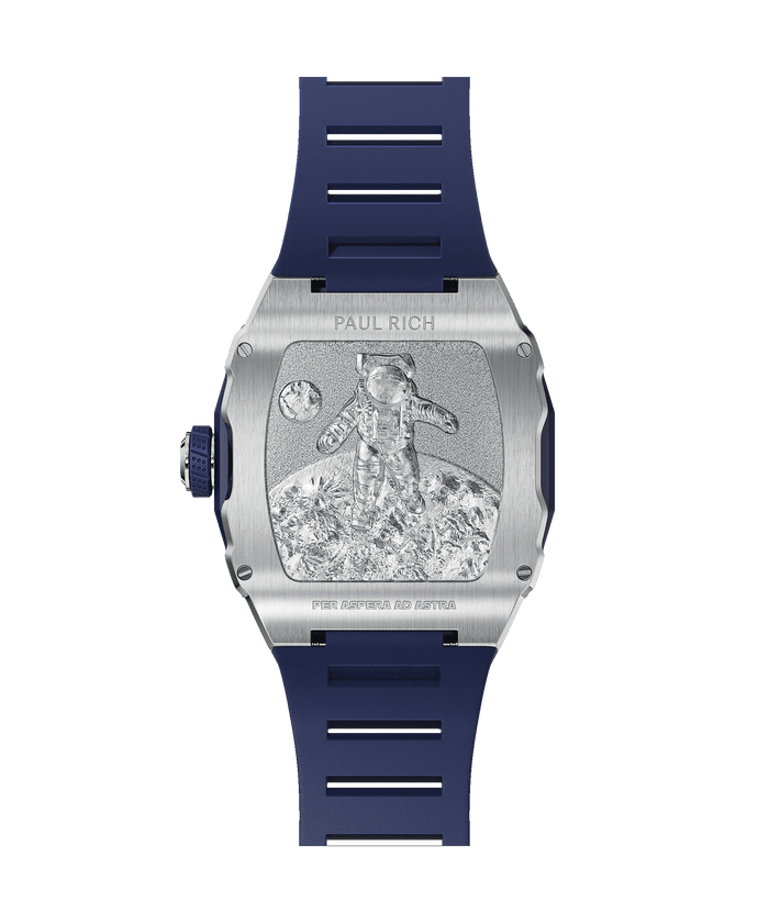 Back of Paul Rich tonneau-shaped watch showing engraved astronaut on lunar surface with 'PER ASPERA AD ASTRA' and blue rubber strap.