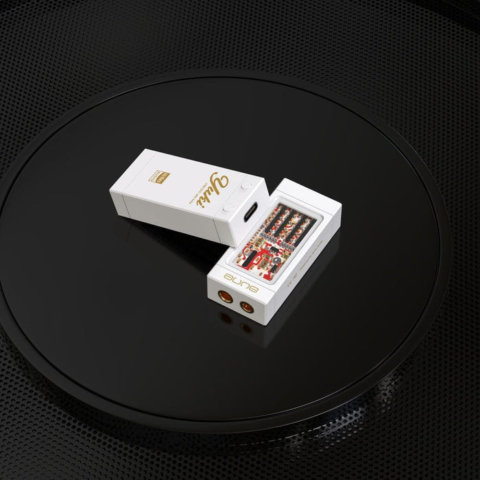 Two white electronic devices, including one with exposed circuitry, rest on a glossy black circular surface with a textured background, highlighting the sleek design of the Aune Audio YUKI Portable DAC and Headphone Amplifier from Aune Audio.