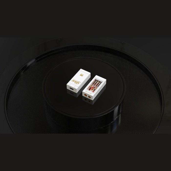 Two compact rectangular boxes, one open to reveal four vape cartridges, are displayed on a glossy black circular surface with a textured pattern—reminiscent of the sleek packaging you’d expect from Aune Audio’s YUKI Portable DAC and Headphone Amplifier.