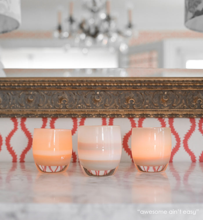 awesome ain't easy sandy yellow hand-blown glass votive candle holder on a marble mantle with a mirror in background.