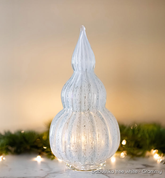 Grammy babushka tree white, with lights and garland in background.