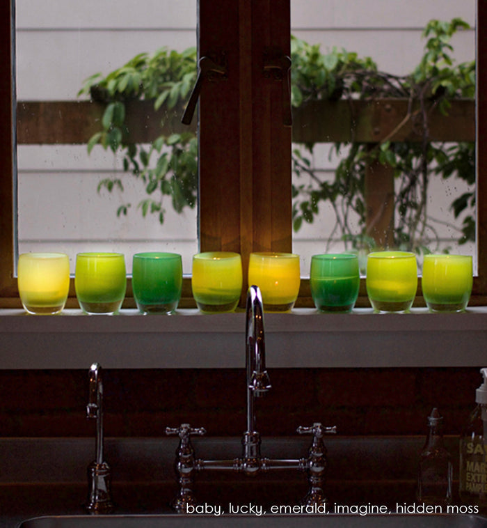 baby light green opaque, soul iridescent translucent, bud pale green opaque, gem green transparent, hand-blown glass votive candle holder on a kitchen sink windowsill with lucky, emerald, imagine and hidden moss.