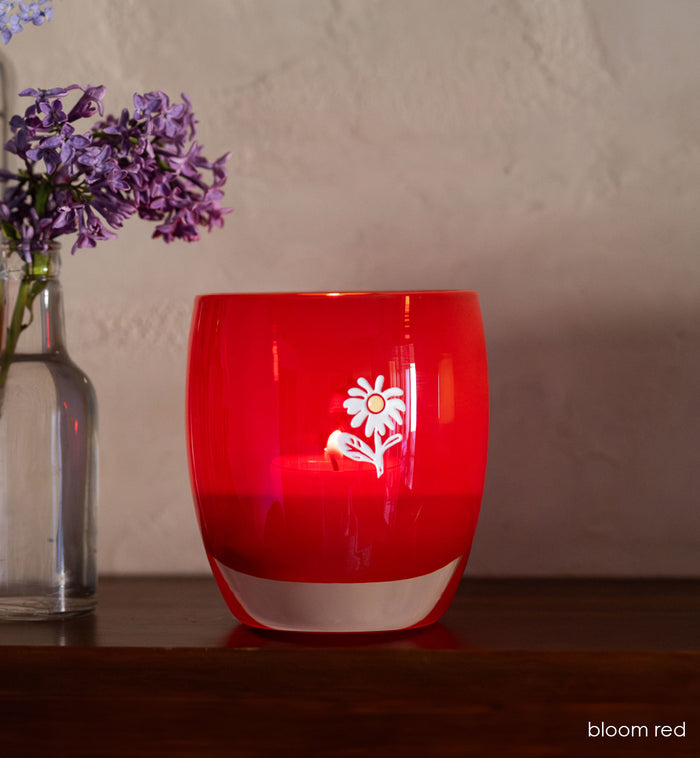 bloom red glassybaby with white flower etched on sitting on wood shelf.