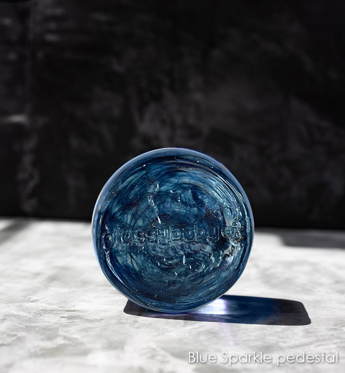 Blue glass pedestal on a white surface with a dark background