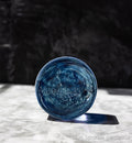Blue glass pedestal on a white surface with a dark background