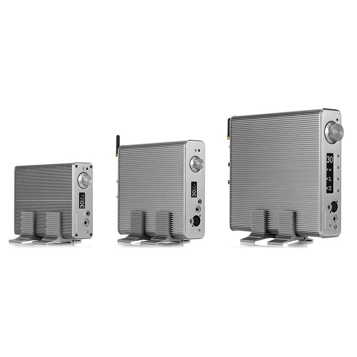 The Burson Audio Cool Stand R (Large) - Clearance by Burson Audio is shown with a ribbed silver metal case, small screen, and multiple control knobs and ports, pictured against a white background in three increasing sizes.