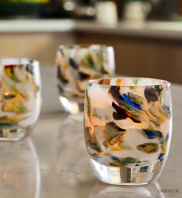 three classical, multi-colored blue marble hand-blown glass votive candle holders on a kitchen island counter.