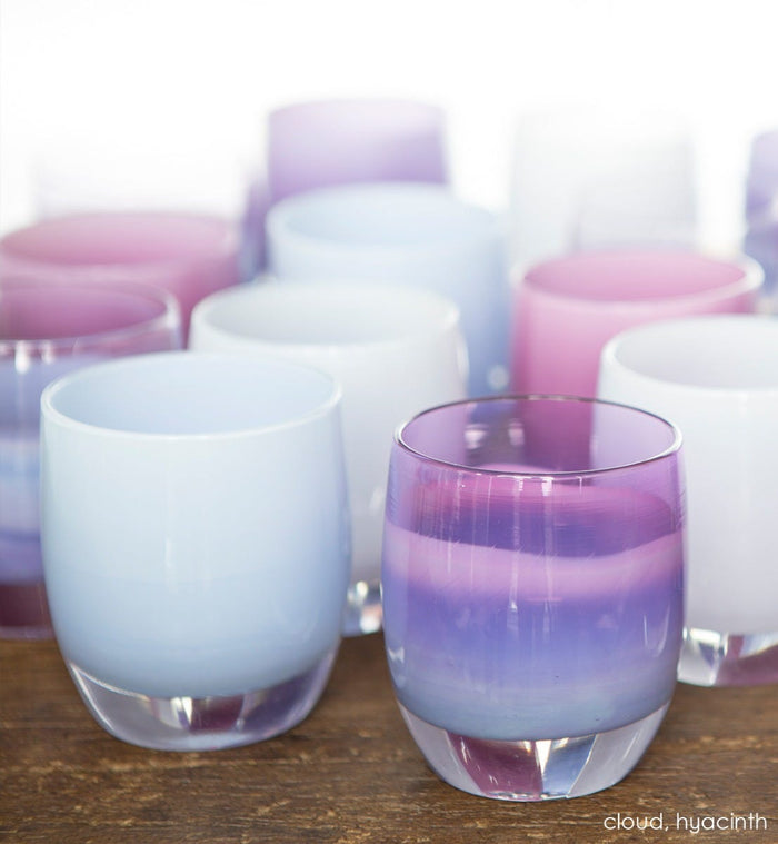 cloud light periwinkle hand-blown glass votive candle holder grouped with hyacinth on wood surface.