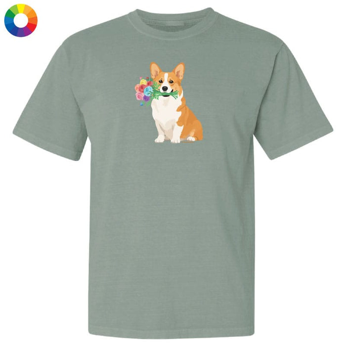 A sage green short-sleeve t-shirt with a graphic of a corgi holding a flower crown on the chest, displayed on a solid white background with a color wheel icon in the top-left corner.