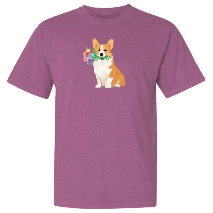 A short-sleeve crewneck t-shirt in a dusty mauve-purple color, featuring a graphic print of a Corgi dog holding a bouquet of colorful flowers on the chest, set against a plain white background.