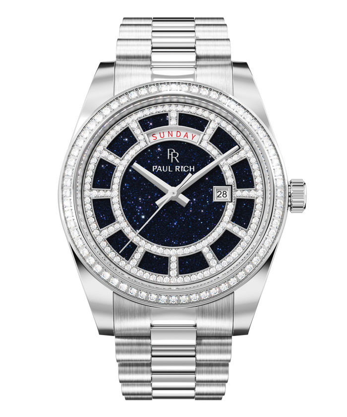 Silver watch with a blue aventurine dial, day and date windows, and a bezel and hour markers set with clear stones on a full stainless-steel bracelet.