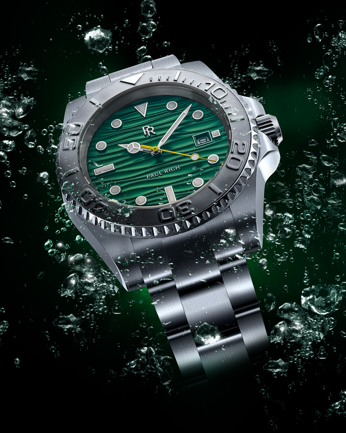Stainless steel watch with a green wave-textured dial shown against splashing green-tinted water on a dark background, highlighting the bezel and bracelet.