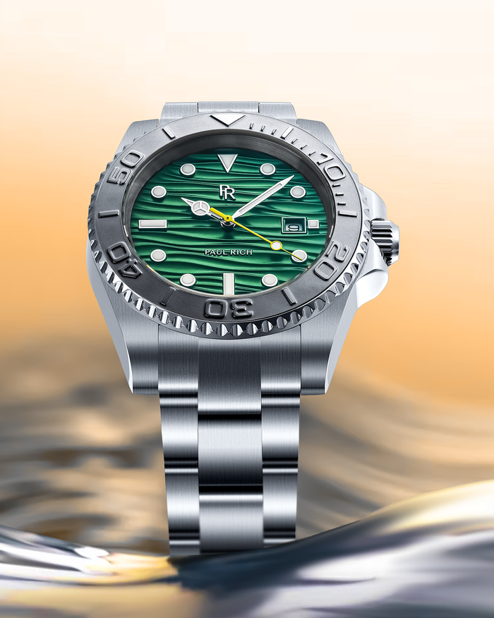 Stainless steel watch with a green wave-textured dial shown above reflective water with a warm sky background, highlighting the bezel and bracelet.