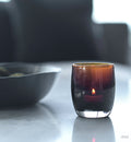 dad translucent dark brown hand-blown glass votive candle holder on marble living room table next to decorative bowl.