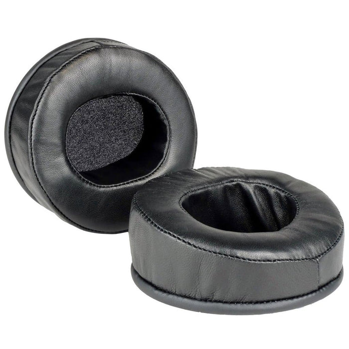 Two black, round Dekoni Audio Elite Sheepskin Ear Pads for Audeze LCD Series are shown, featuring soft memory foam and a leather-like sheepskin surface; one stands upright while the other lies flat to display the inner cushion.