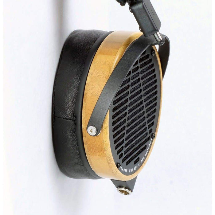 Close-up of a Dekoni Audio Elite Sheepskin Ear Pad for Audeze LCD Series, showing its plush black sheepskin cushioning, sleek wooden earcup ring, black metal grille, and comfortable memory foam padding.