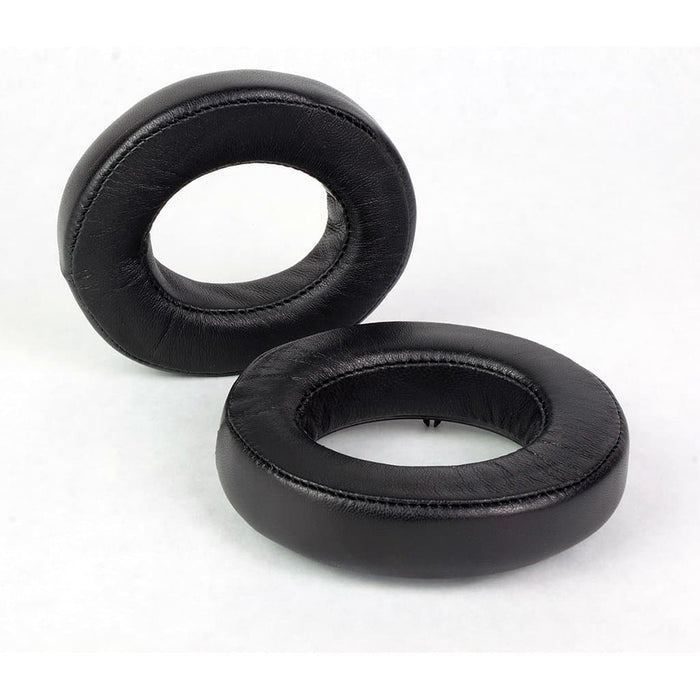 Two black oval Dekoni Audio Elite Sheepskin Ear Pads for Focal headphones, compatible with Utopia, are shown—one upright and one flat on a white background.