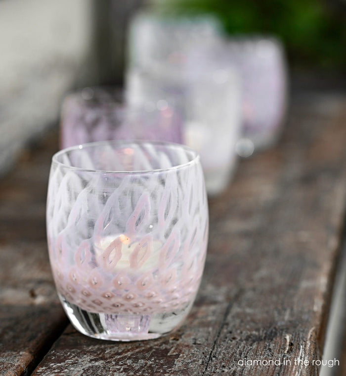 diamond in the rough, light pink bubble, hand-blown glass votive candle holder on a wood bench, with yes and diamond in the rough blurred in background.