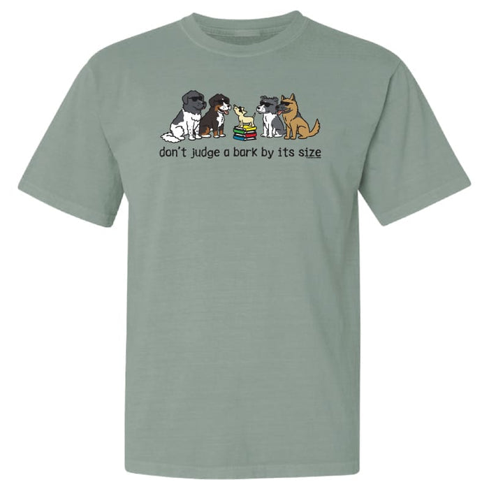 A sage green short-sleeve t-shirt with a graphic of four different dog breeds sitting next to each other and the text 'don't judge a bark by its size' printed below them.