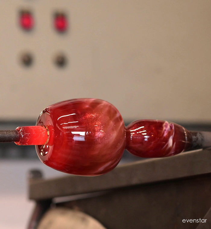 evenstar pink and gold glitter hand-blown glass votive candle holder in the middle of the glassblowing craft process.