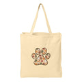 A natural canvas tote bag with a large paw print graphic on the front, filled with a colorful autumn-themed pattern of pumpkins, leaves, and fall foods, shown against a plain white background.
