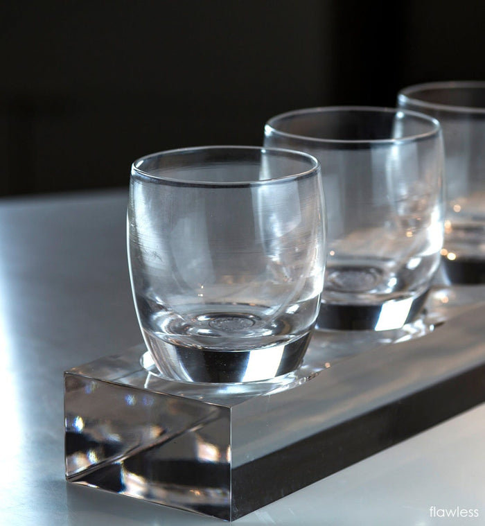 three flawless transparent crystal clear hand-blown glass votive candle holders on an acrylic square stand.