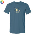 A slate blue crewneck t-shirt featuring a cartoon graphic of a dog sitting on a blanket with seagulls flying around, and the text 'flock off' printed below. A small circular color wheel icon is visible in the top-left corner.