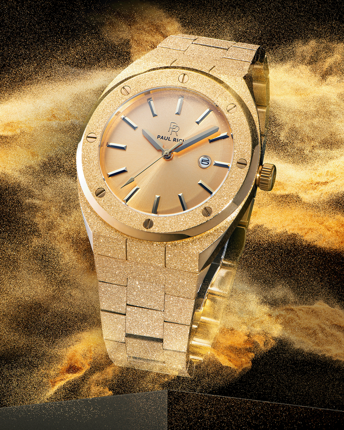 Paul Rich watch with frosted gold case and bracelet, metallic champagne gold sunray dial, and date window, shown in golden sandburst explosion on black.