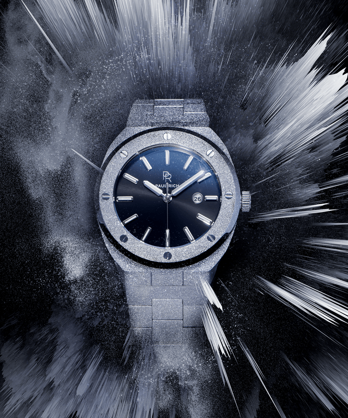 Paul Rich watch with frosted silver case and bracelet, metallic black sunray dial, and date window, displayed in a dynamic icy burst effect on dark background.