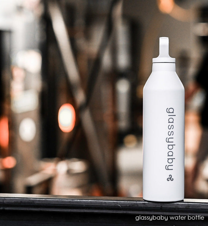 glassybaby water bottle on a black surface with glassybaby hotshop in background.