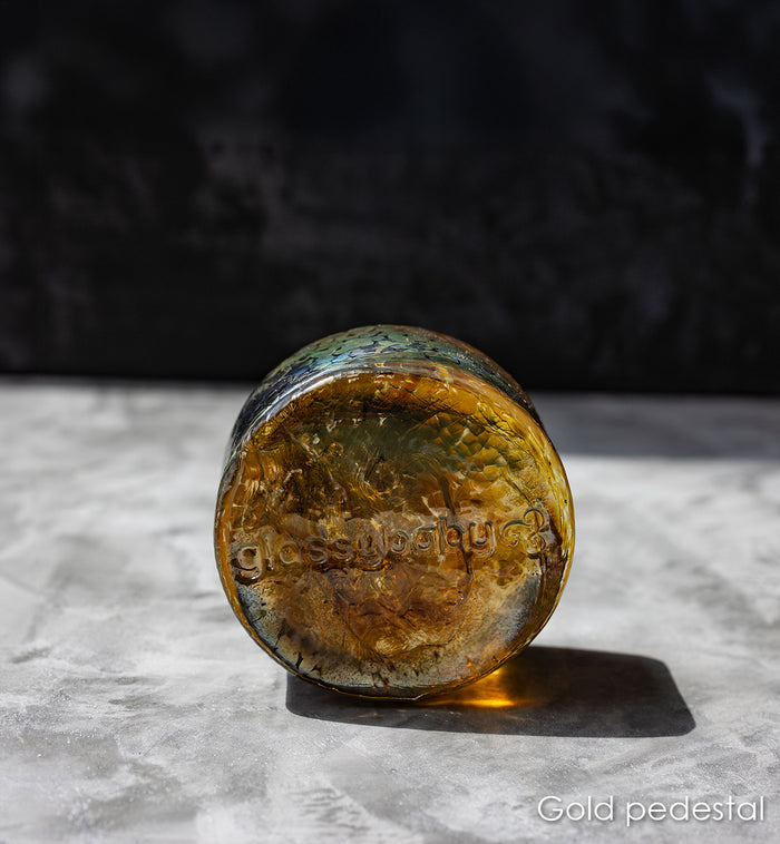 Gold pedestal on a textured surface with a dark background