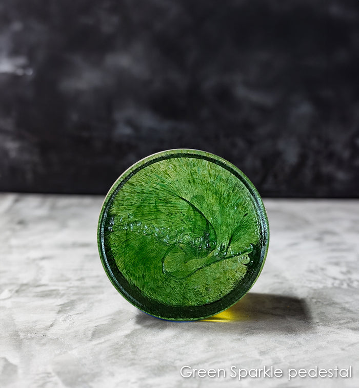 Green sparkling pedestal on a gray surface with a dark background