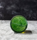 Green sparkling pedestal on a gray surface with a dark background