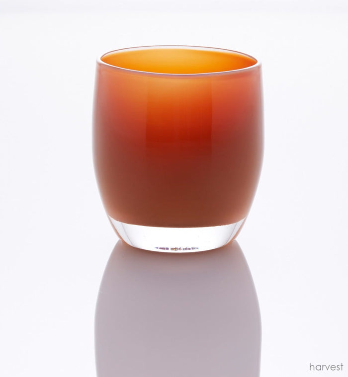 harvest deep orange hand-blown glass votive candle holder in a white setting.