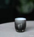 haunted black double overlay hand-blown glass votive candle holder on a marble table outside.