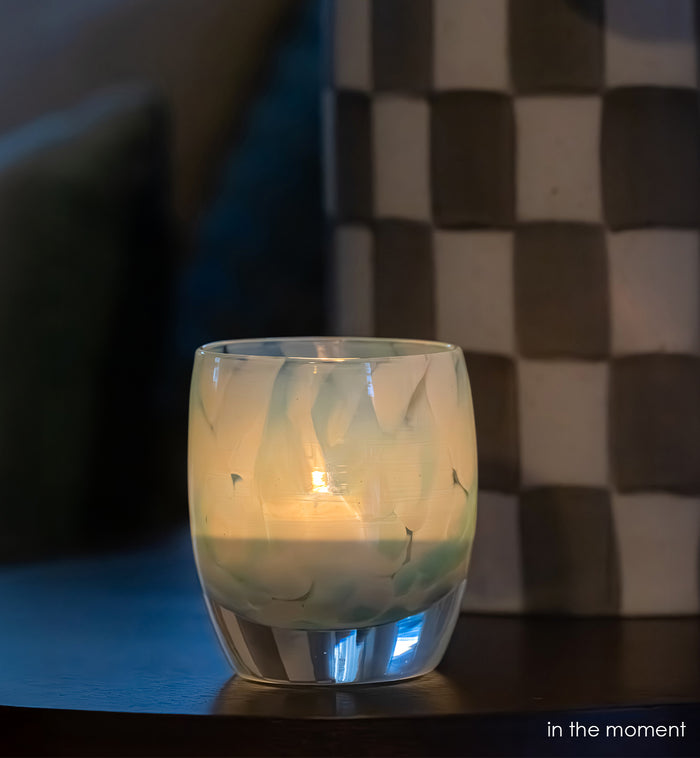 in the moment, blue, white, hand-blown glass votive candle holder with a lit candle on a wooden surface, dark background