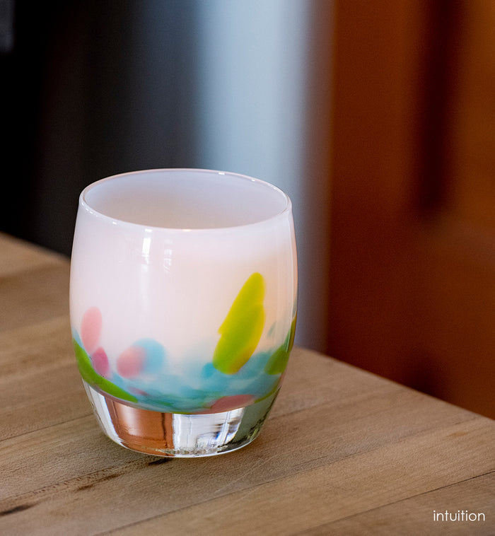 intuition blue, green and pink petals of color at the base of a white, hand-blown glass votive candle holder