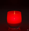 joy crimson red hand-blown glass votive candle holder on a reflective surface.
