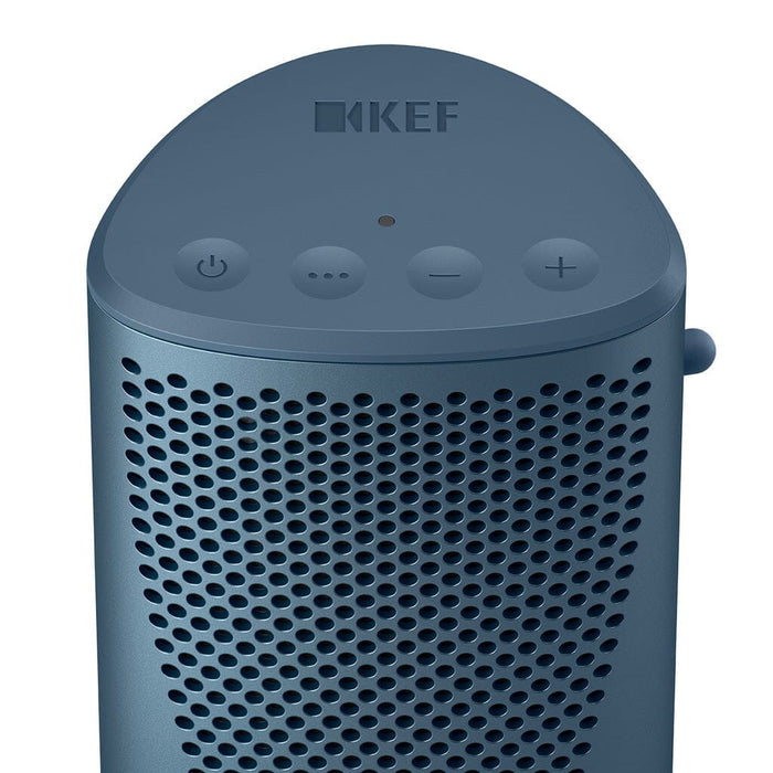 Close-up of a blue KEF Muo HiFi Portable Bluetooth Speaker with the brand name and four top buttons—power, multifunction, volume down, and volume up. The front displays a perforated grille design.