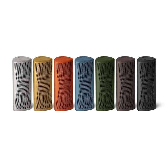 Seven KEF Muo HiFi Portable Bluetooth Speakers by KEF, each in white, yellow, orange, red, blue, green, brown, and black with a perforated front and curved design, are lined up on a white background.