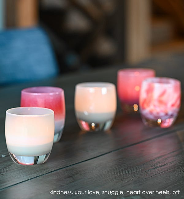 kindness soft cream hand-blown glass votive candle holder. Paired with your love, snuggle, heart over heels, and bff on a long gray wood table.