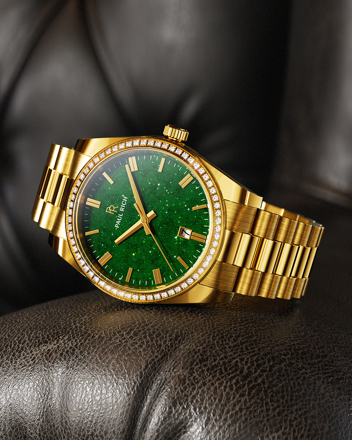 Gold-tone Paul Rich watch with green aventurine dial, diamond-set bezel, and gold link bracelet, displayed resting on a dark brown leather cushion.
