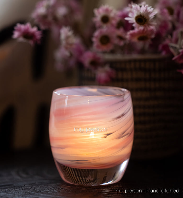 Glass candle holder with marbled design and 'my person' hand etched on a blurred background