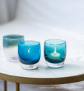 night out dark aqua blue transparent, hand-blown glass votive candle holder. paired with mother earth metallic blue green on white, and beach house blue gradient