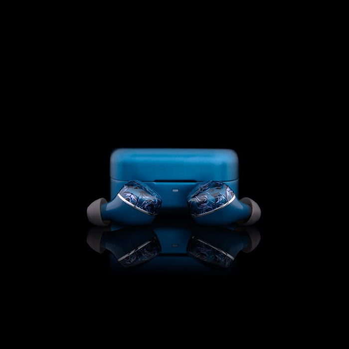The Noble Audio Osprey Wireless In-Ear Headphones by Noble Audio, in blue with silicone tips, are displayed on a glossy black surface with their matching charging case. Featuring a hybrid driver design, they offer enhanced sound quality.