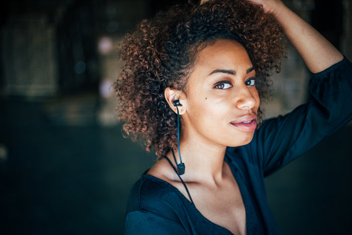 Model wearing black Omen wireless earbud. She is looking into the camera.