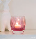 petunia transparent light pink hand-blown glass votive candle holder with white bunny behind it.