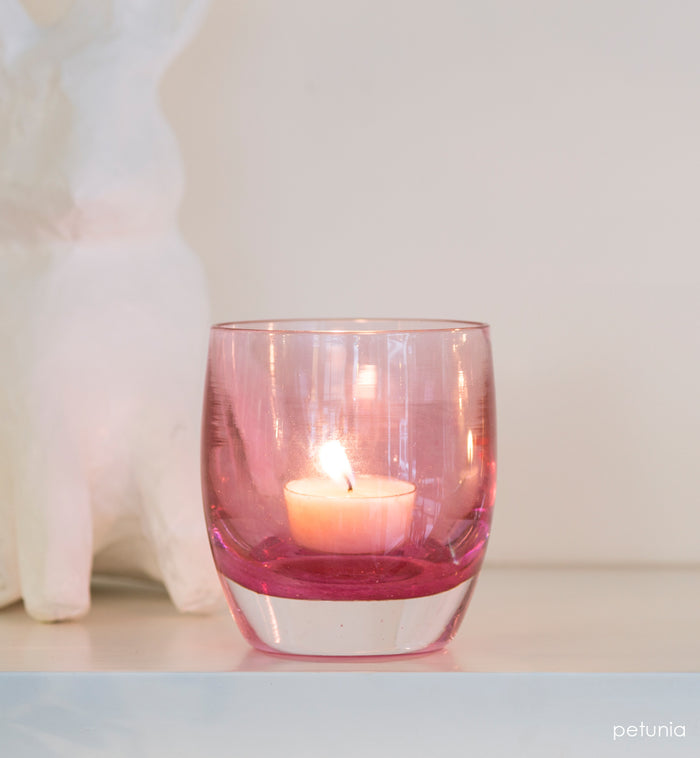 petunia transparent light pink hand-blown glass votive candle holder with white bunny behind it.
