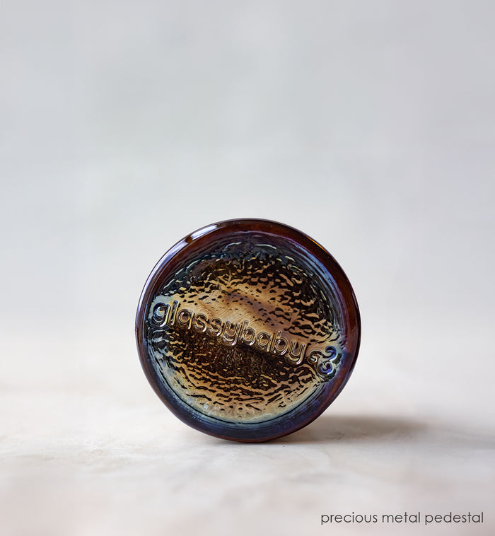 Round metallic object with textured surface on a light gray background